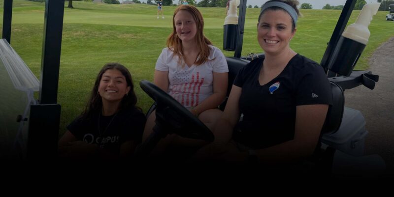 three females in a golf cart